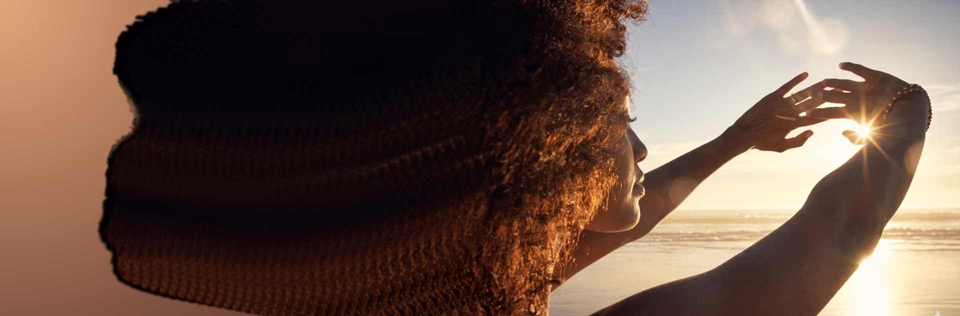 Mujer sosteniendo la luz del sol entre sus manos al atardecer con la energía de Vibra Mobile