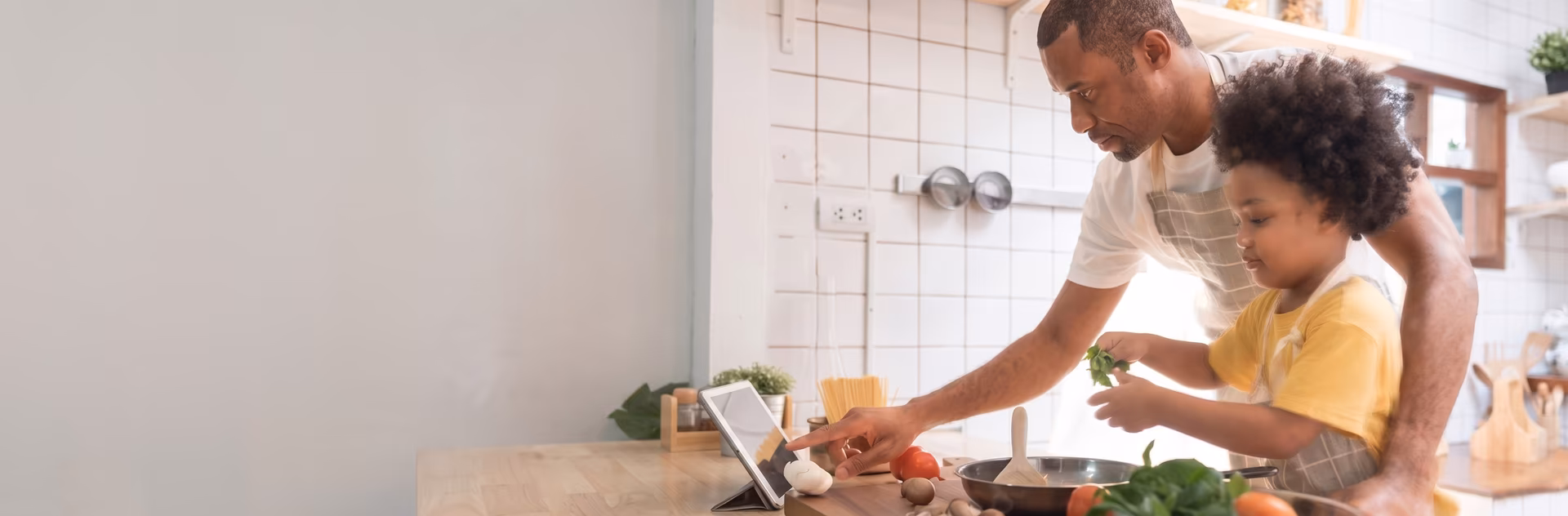 Padre e hijo cocinando juntos en casa con tablet, disfrutando de la fibra y móvil de Vibra Mobile